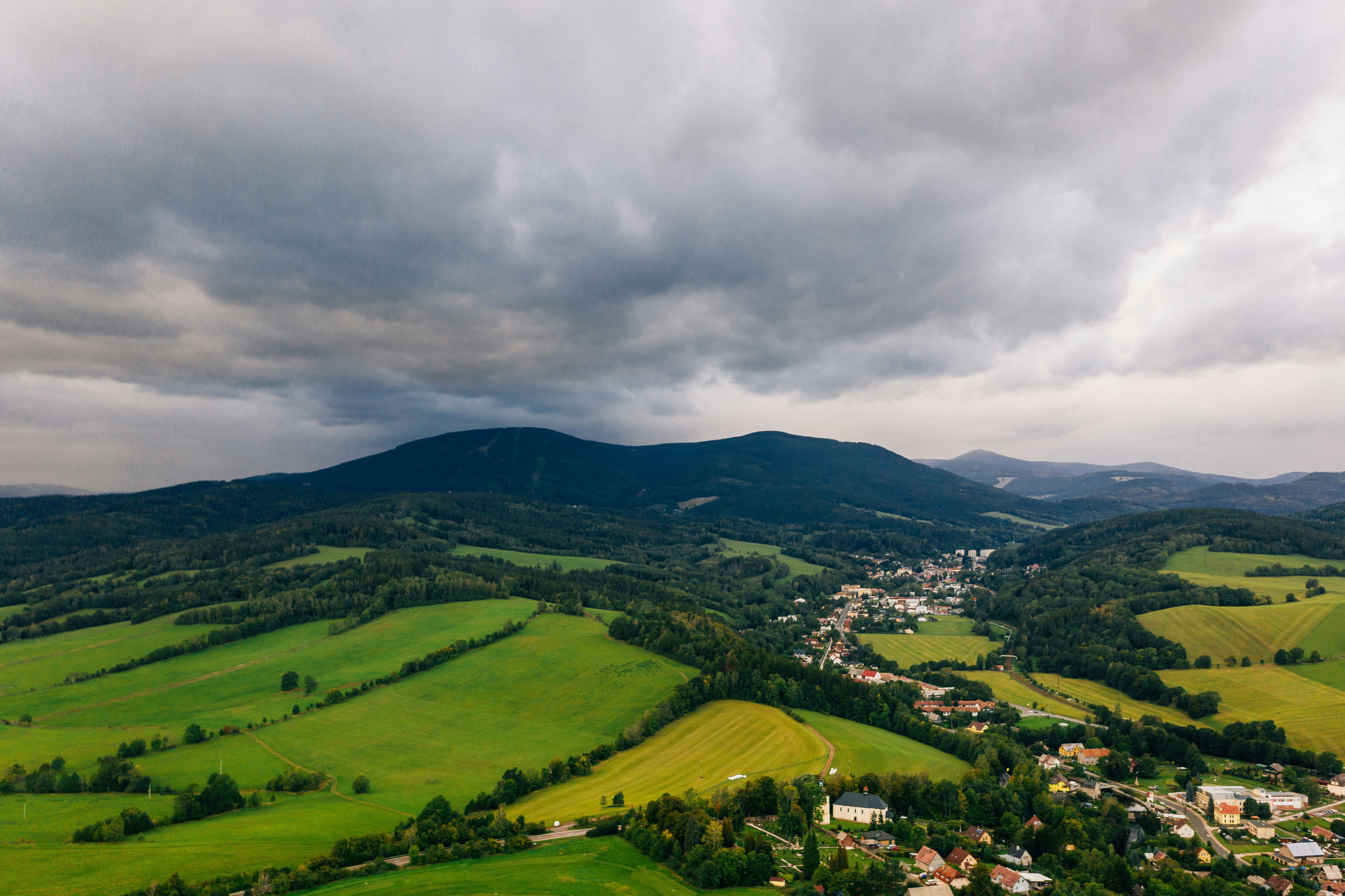 aerial photography of houses surrounded by trees under cloudy sky during daytime